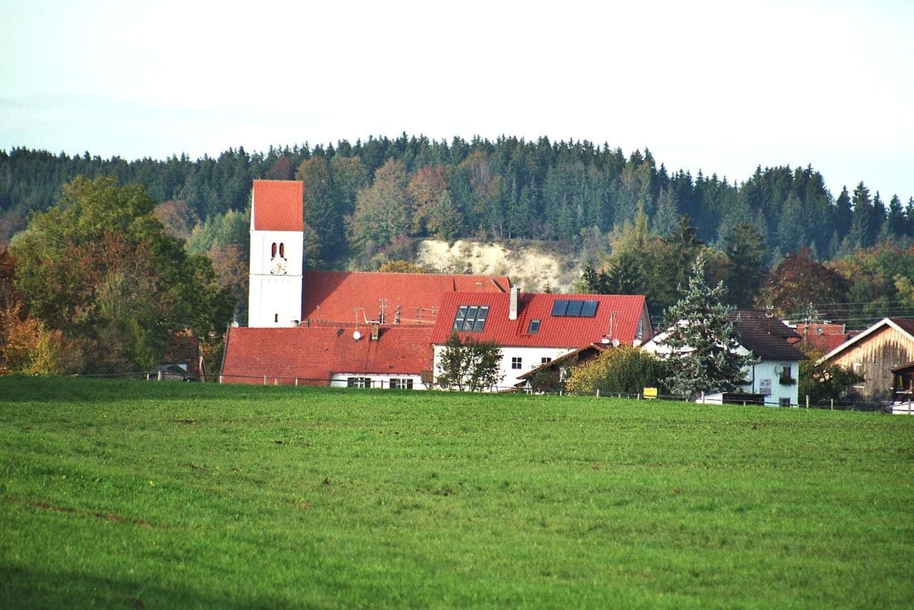 Blick über Apfeldorf zur Pfarrkirche Heilig Geist mit ihrem Kirchturm.